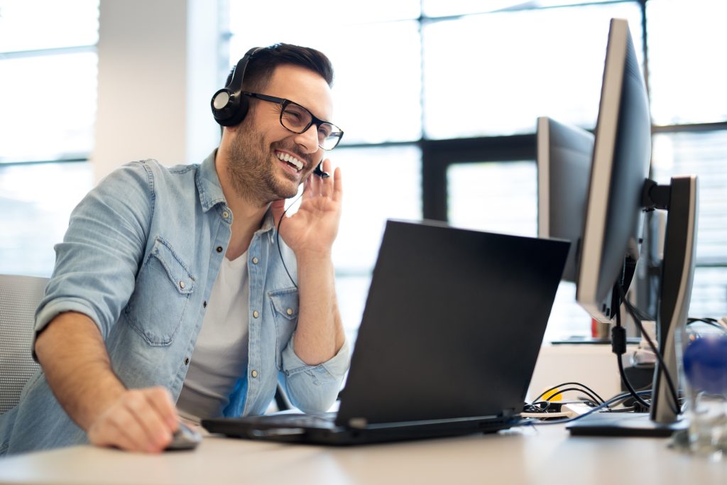 Young smiling male call center operator doing his job with a hea | Quest Mindshare Friendly client call showing how a market research partner builds rapport