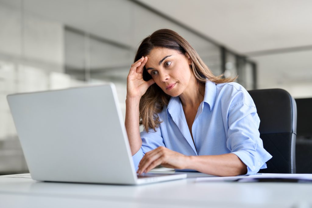 Worried fatigued middle aged business woman having headache at work | Quest Mindshare Frustrated respondent reacting to common survey design mistakes