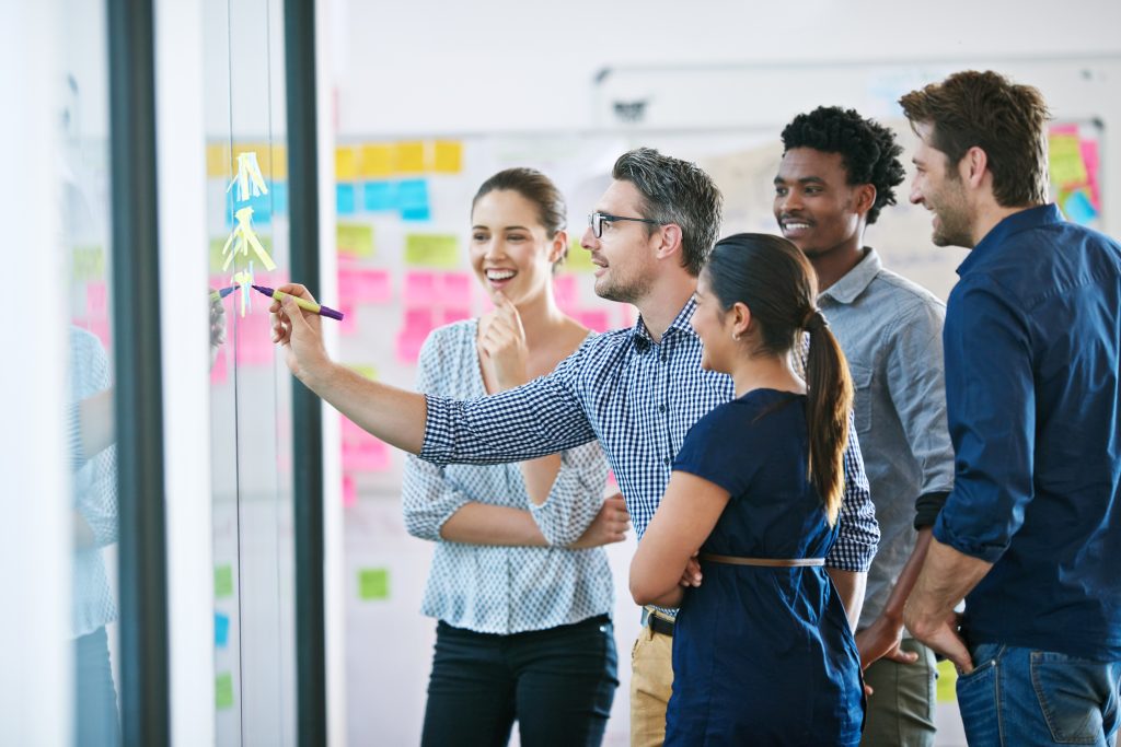Discussion glass wall and team of business people in office planning creative strategy for brand management Meeting ideas and group of public relations specialists by board for project at startup | Quest Mindshare Research team reviewing quota results to build a representative sample